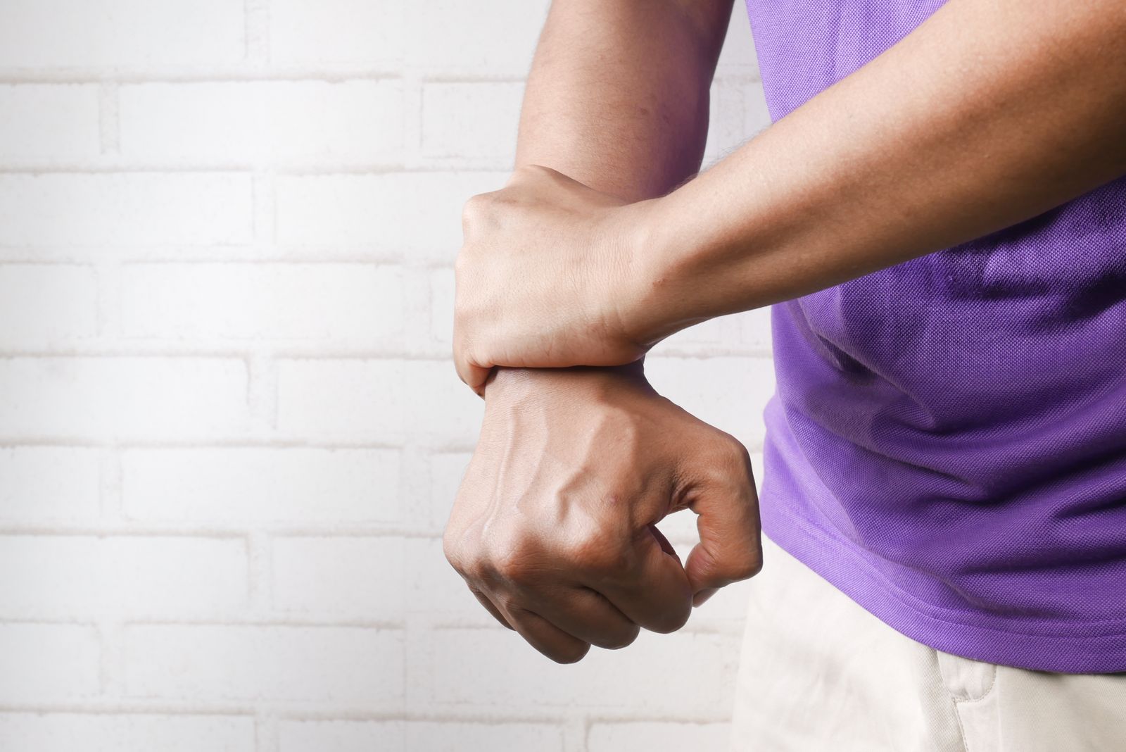 Persona sujetándose la muñeca por dolor — tendinitis de De Quervain